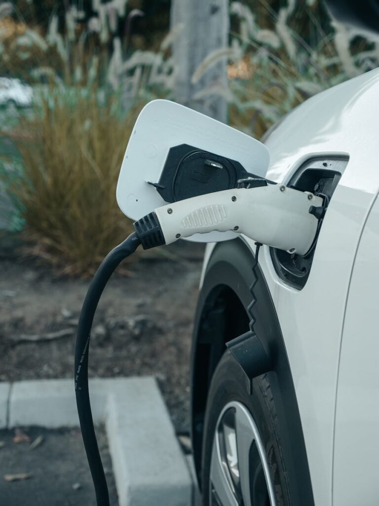 Close-up of electric vehicle connected to charging station outdoors.