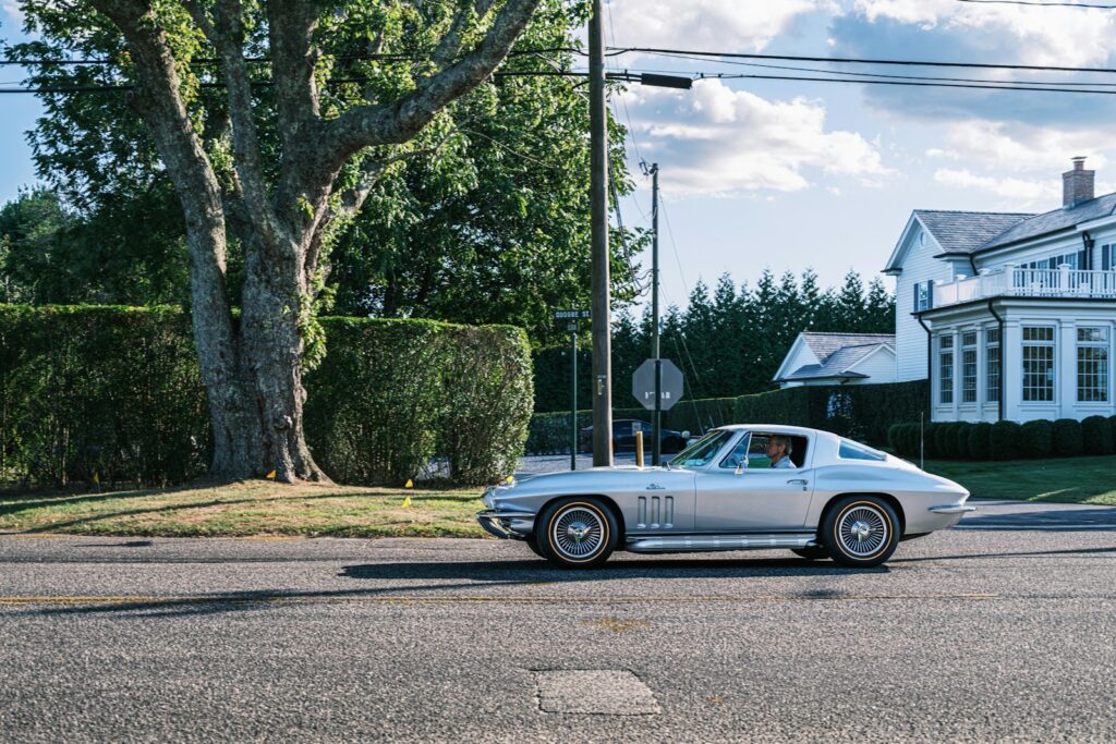 Silver vintage car driving on a sunny day.