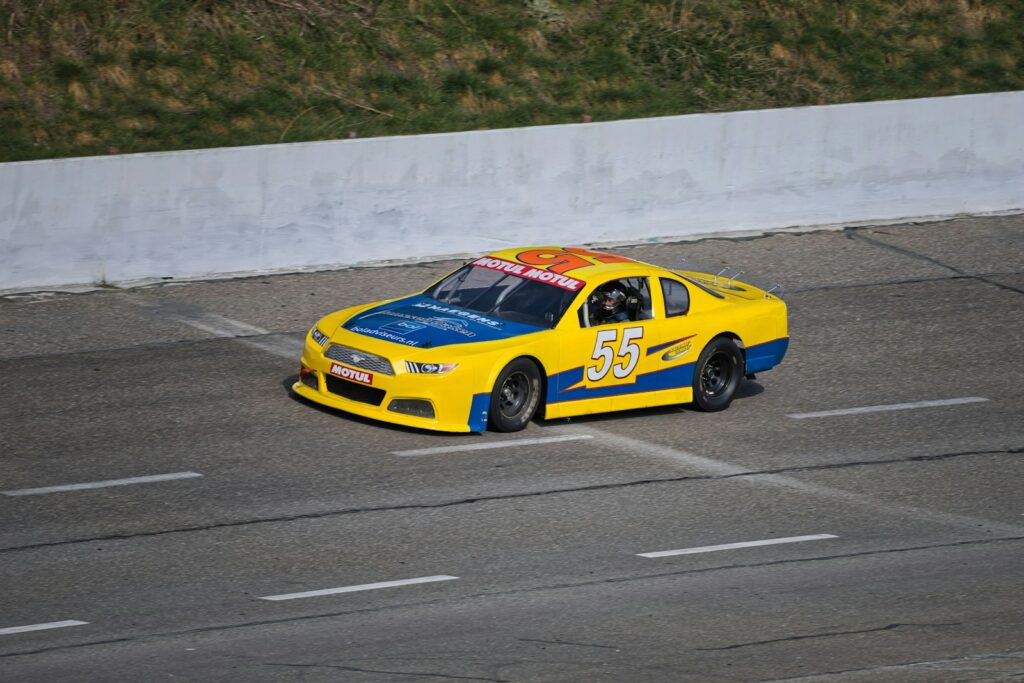 A yellow race car with the number 55 on it.
