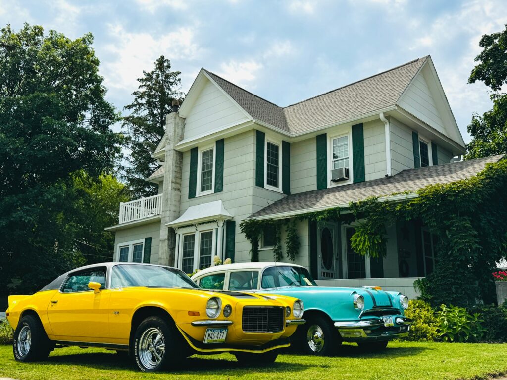 Two vintage cars parked in front of a large house.