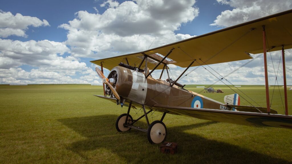 Classic vintage biplane parked on grassy field in Poland during daylight with a clear sky.