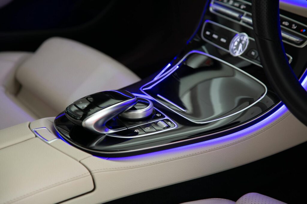 Close-up of a sleek car console featuring elegant design and ambient blue LED lighting.