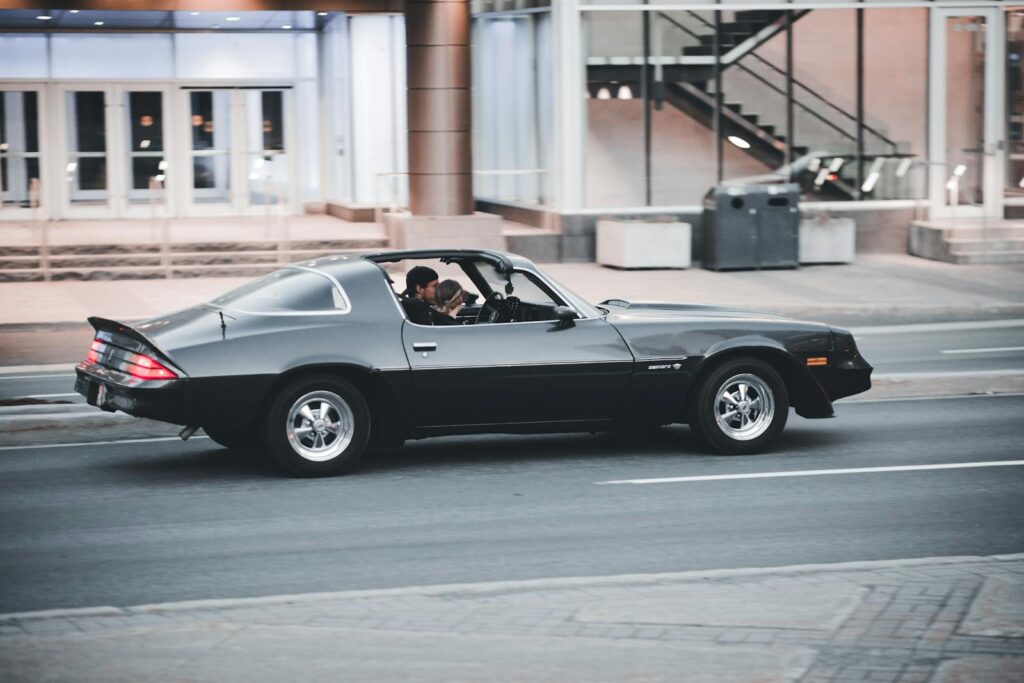 Classic Chevrolet Camaro in motion showcasing vintage style and urban backdrop.