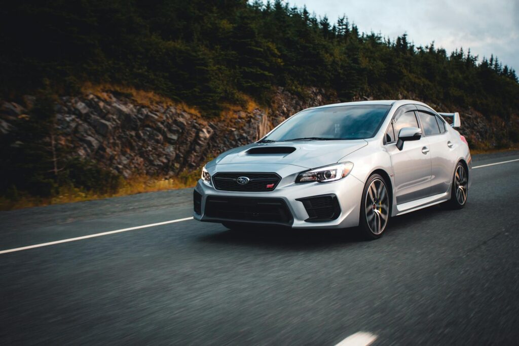 Captivating shot of a Subaru WRX STI speeding along a scenic forest highway, showcasing its sleek design.