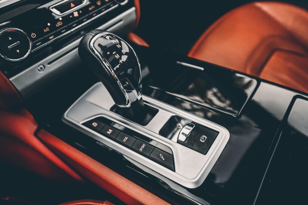 Close-up of a luxury car's gear shift and dashboard, highlighting elegant design and premium materials.