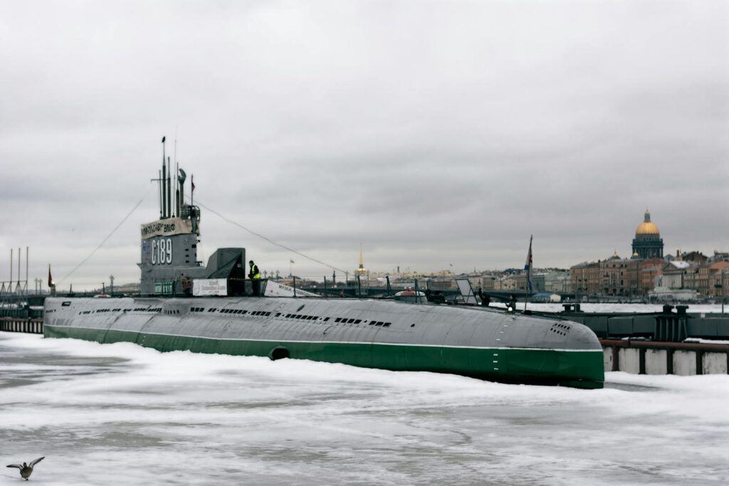 Submarine surrounded by ice in Saint Petersburg with historic cityscape in background.