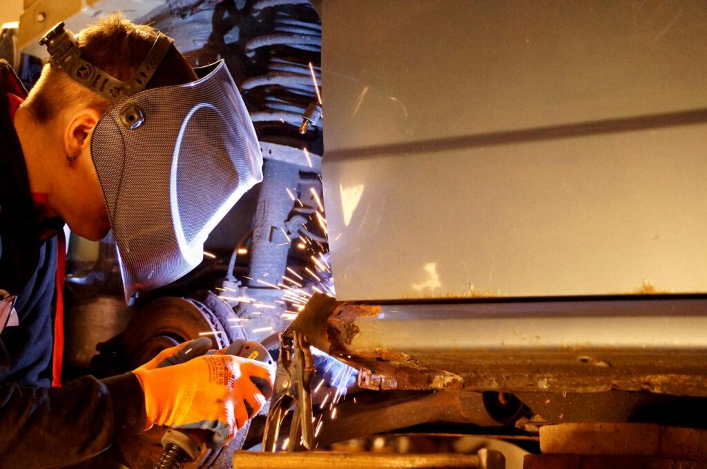 A skilled welder wearing protective gear working on metal with sparks flying in an industrial setting.