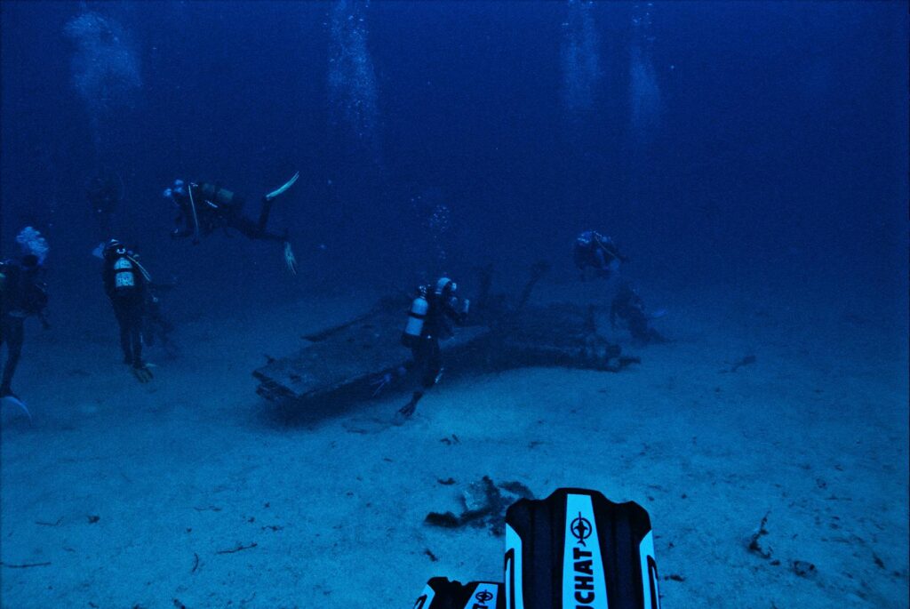 Divers exploring underwater wreckage during a deep ocean scuba dive.