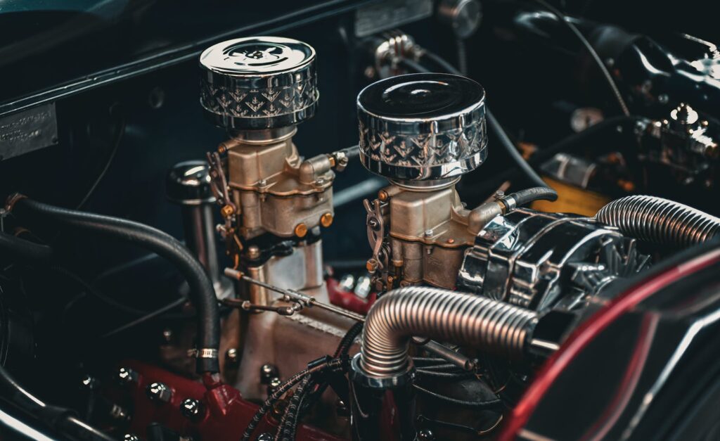 Close-up of a classic car engine showcasing intricate details of twin carburetors and metallic components.
