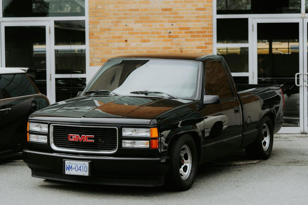 A sleek black GMC pickup truck parked outside a commercial building.