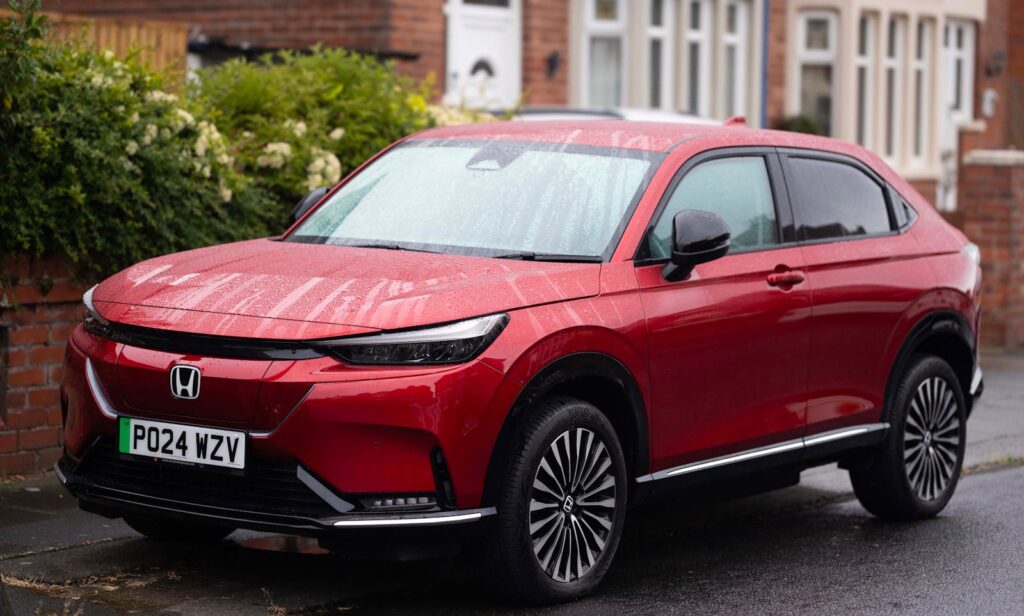 A vibrant red Honda SUV parked on a rainy suburban street, showcasing modern design.