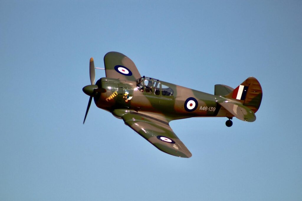 A classic military fighter plane in flight against a clear blue sky, showcasing its vintage design and markings.