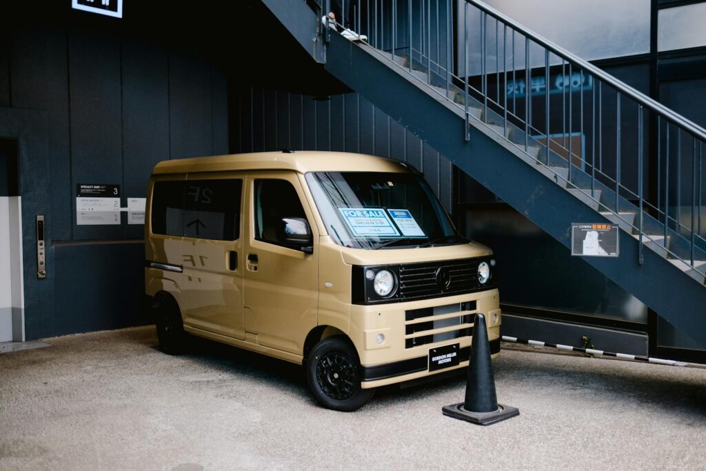 A tan van parked in an urban garage, ready for sale. Modern city setting.