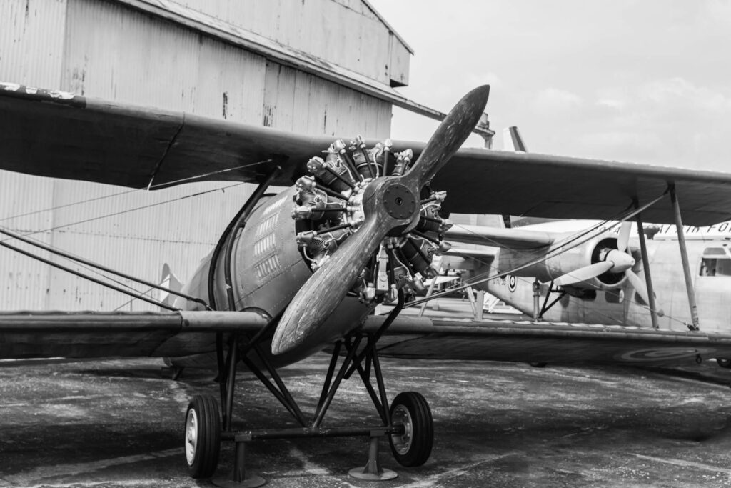 Black and white image of a vintage biplane on display at an aviation museum.