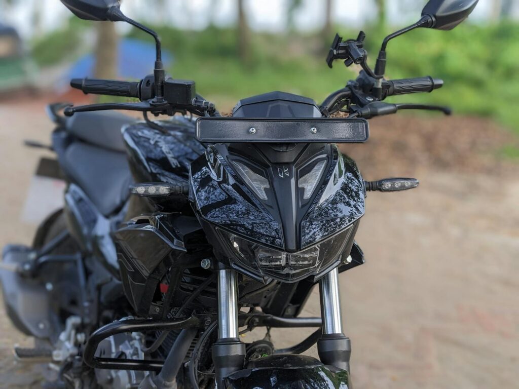 Close-up view of a black motorcycle parked outdoors with blurred natural background.