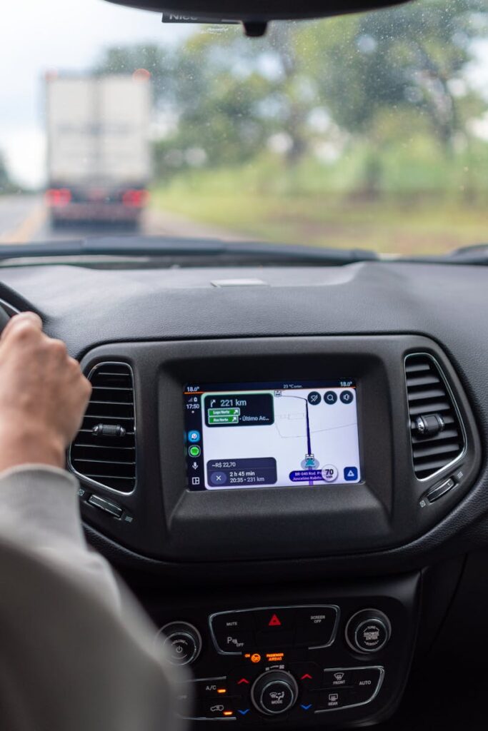 View of GPS navigation screen inside a moving car with driver on the road.