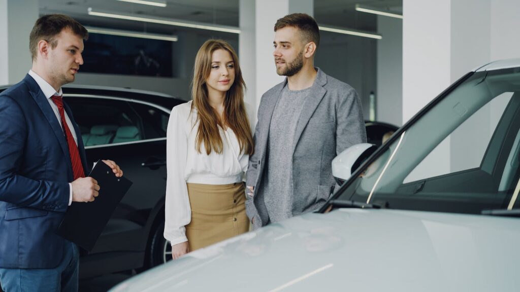 Couple discussing options with a car salesman inside a dealership.