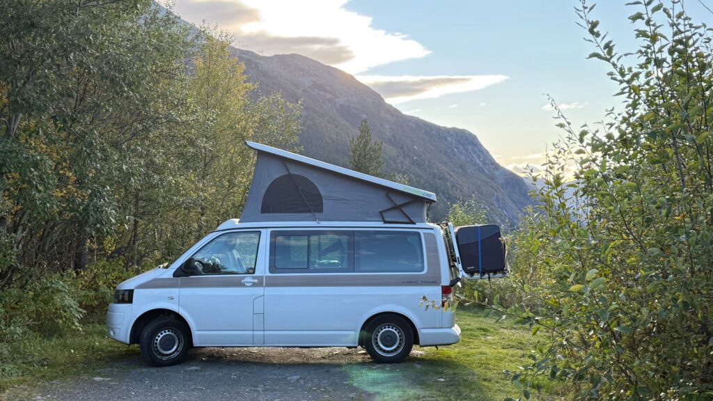 A camper van parked amidst picturesque mountains during a serene day outdoor adventure.
