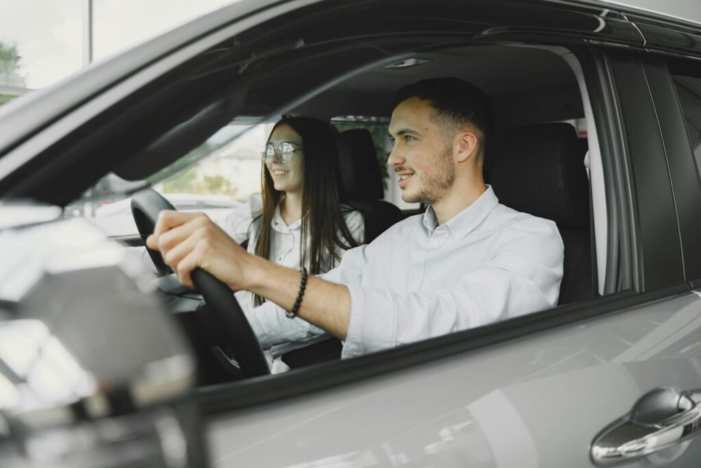 A young couple smiling while driving together in a modern car interior.
