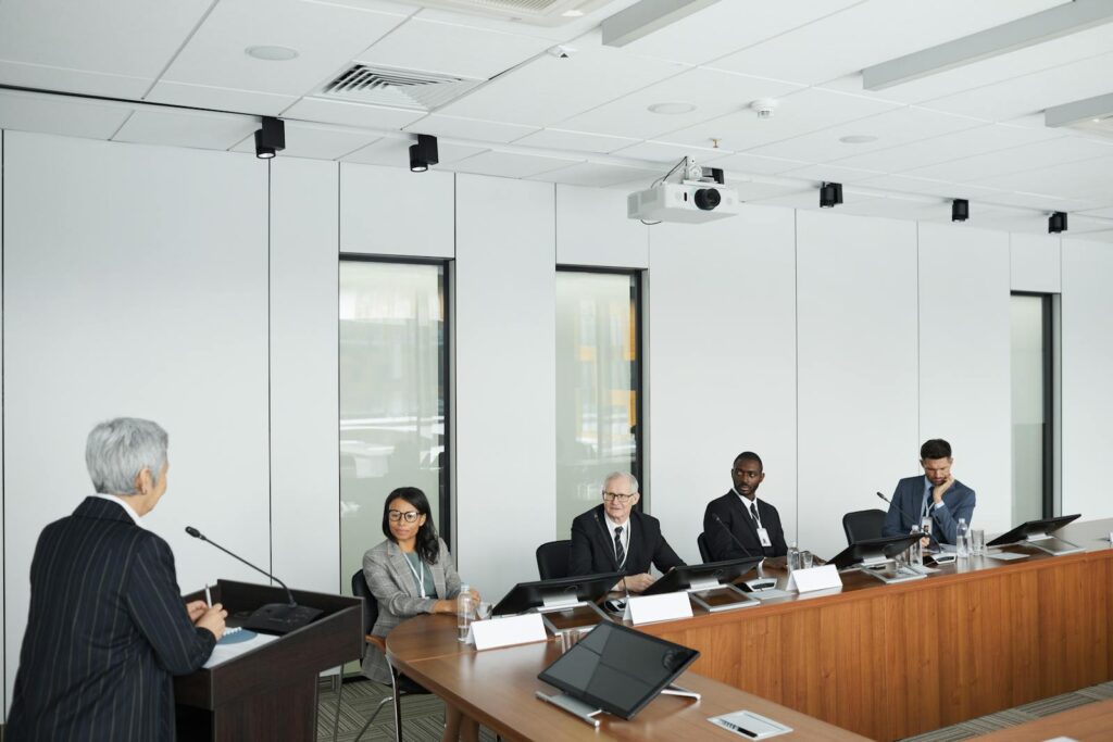 Business meeting with diverse panel and a speaker in a modern conference room.