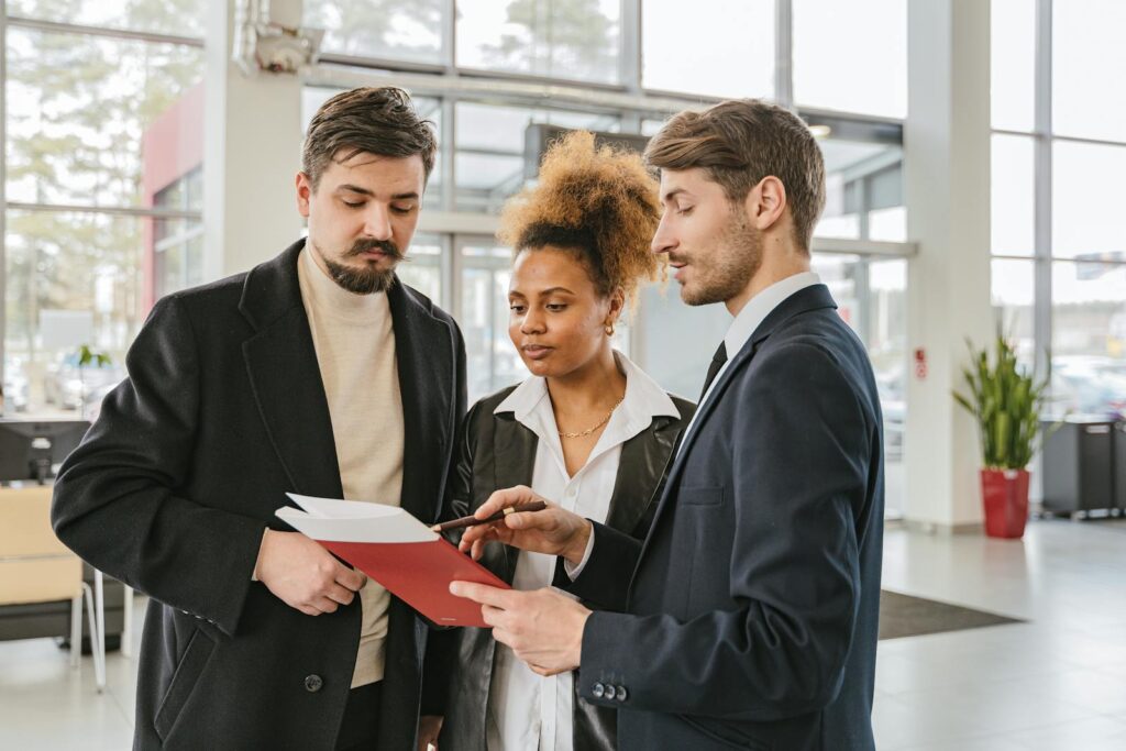 Three professionals discuss documents in a modern office setting, highlighting teamwork and collaboration.