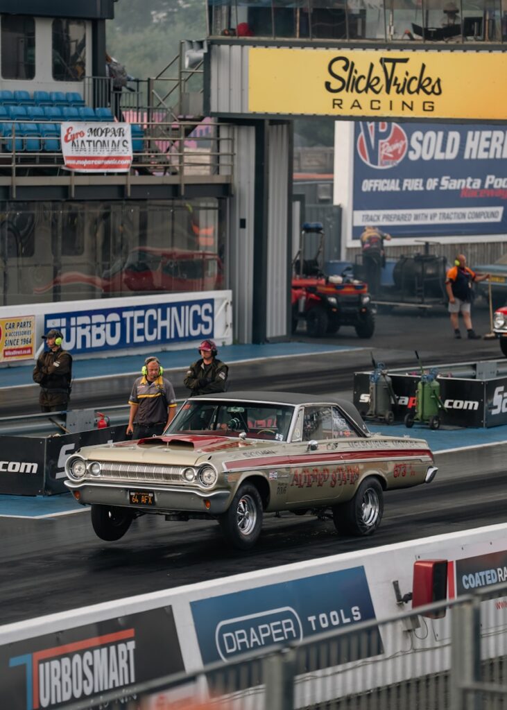 A vintage car races down the drag strip.