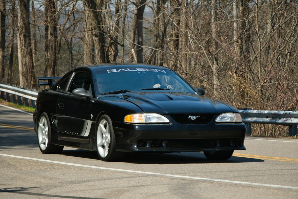 Black saleen mustang drives on a road