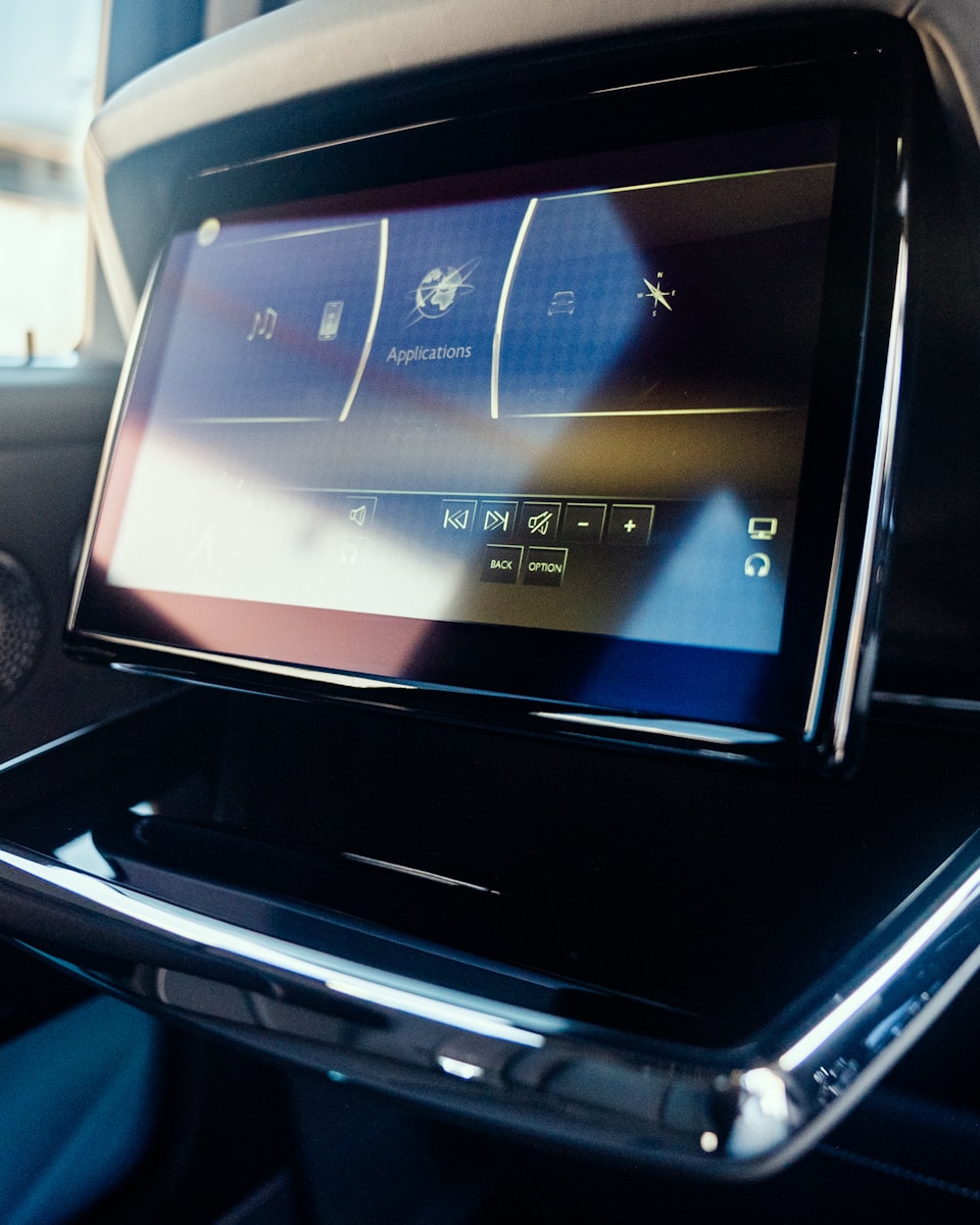 An interior car screen displays applications.