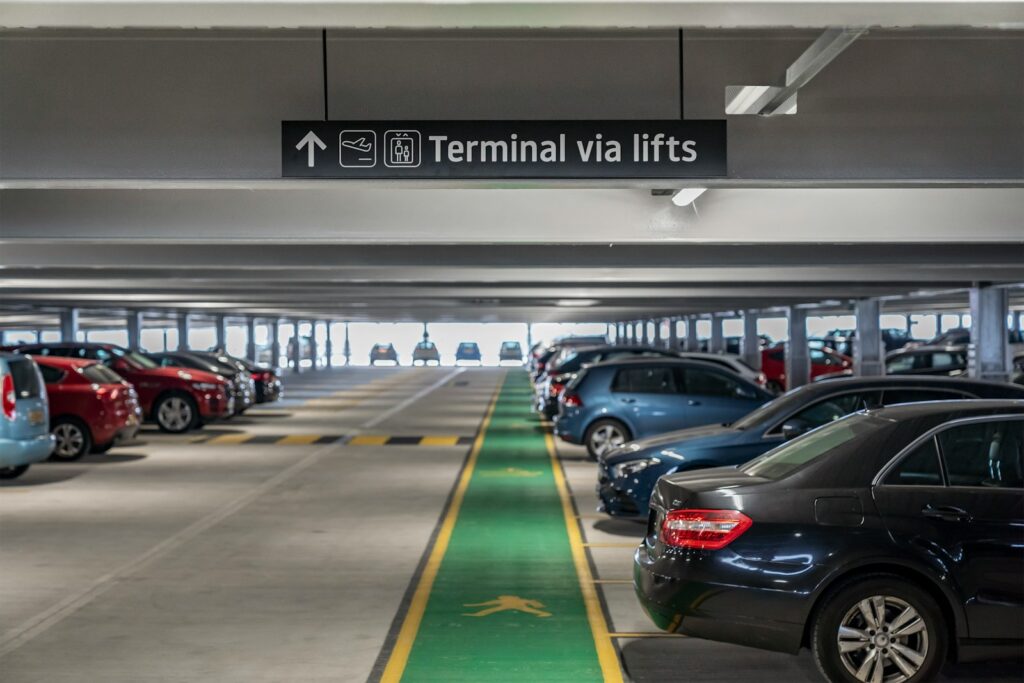 Cars parked in a multi-level parking garage with directional signage.