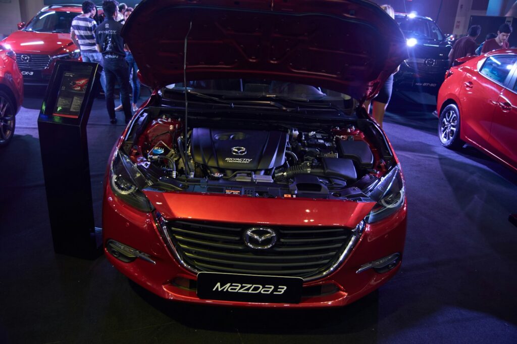 A red car with its hood open in a garage