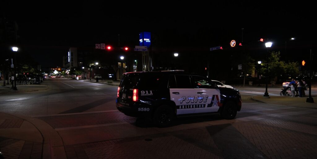 Police car driving on a city street at night.