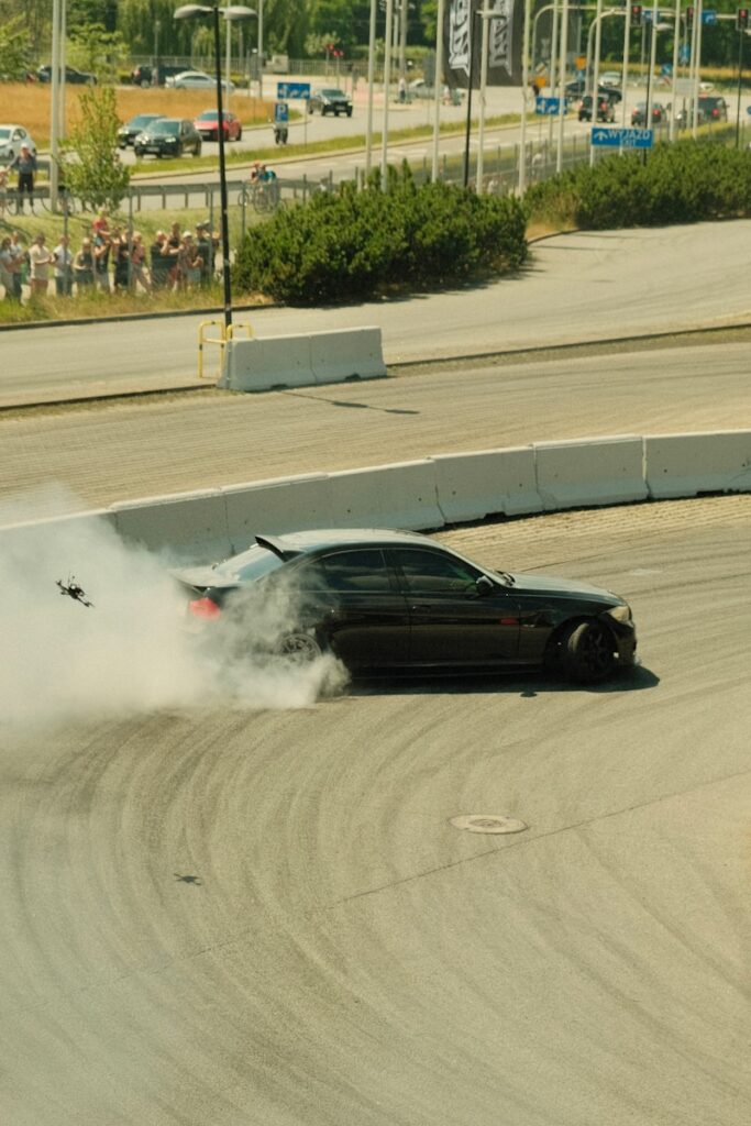 A car drifts around a track, creating smoke.