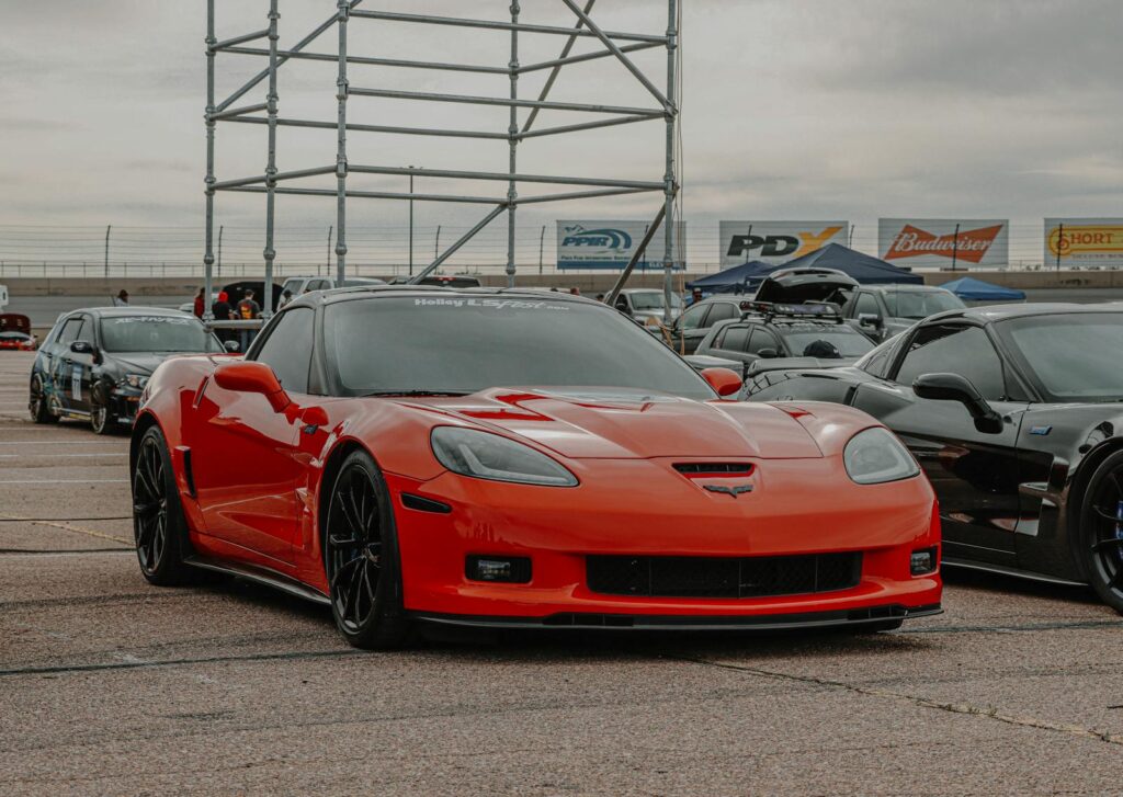 Red Corvette sports car parked at a daytime automotive event, showcasing its sleek design.