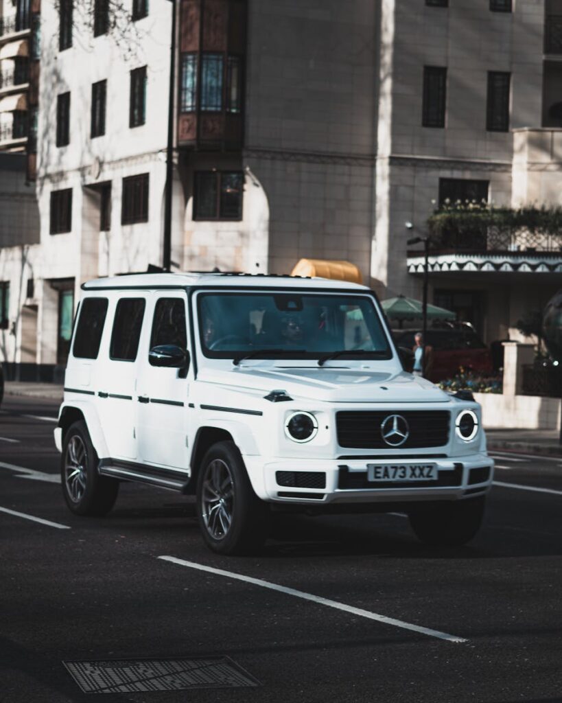 A sleek white luxury SUV navigating through an urban city street.