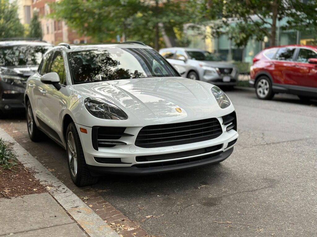A white porsche cayen is parked on the side of the street