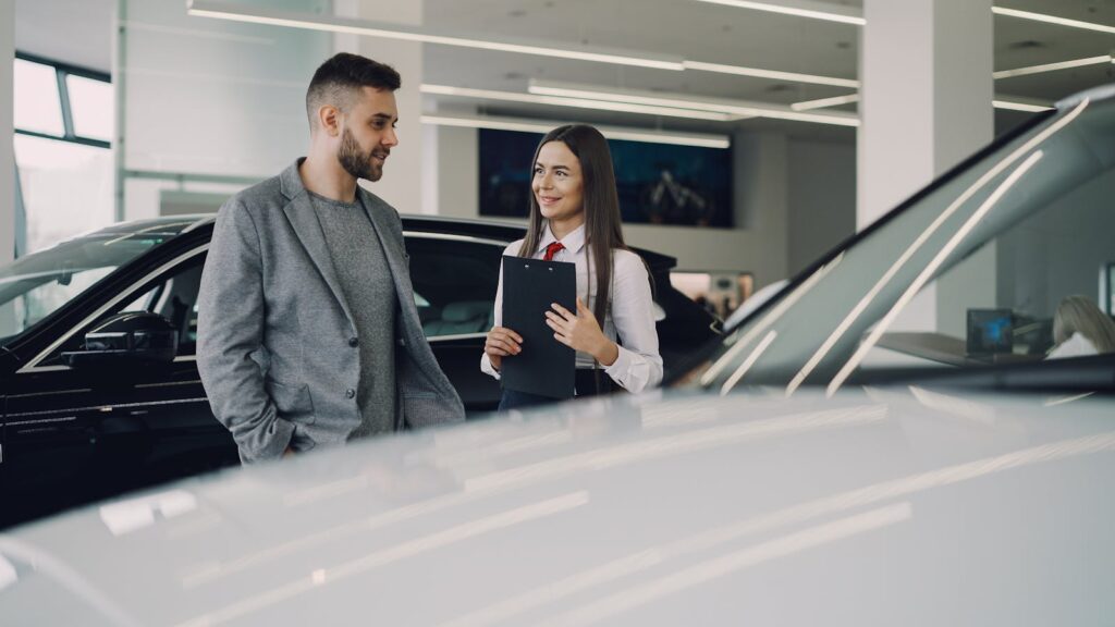 Man consults with salesperson in modern car dealership showroom.
