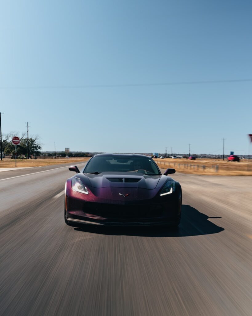 A purple sports car driving down a road