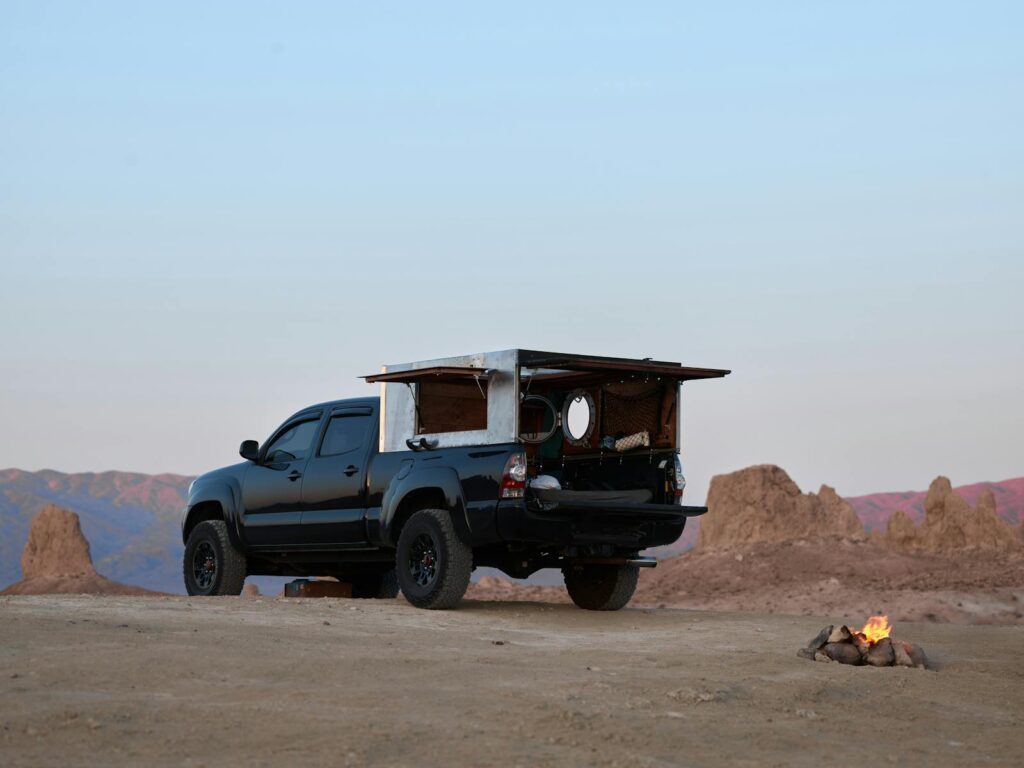 Adventure scene of an off-road pickup truck camping in a desert landscape with a small bonfire.