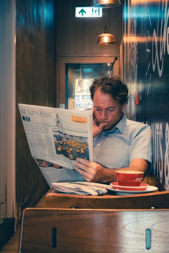 Man reading newspaper with coffee at cafe