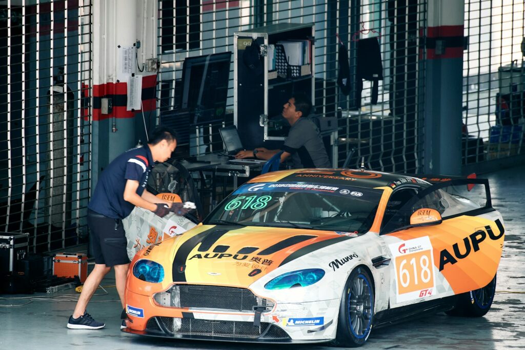 Mechanics cleaning a race car in a garage.