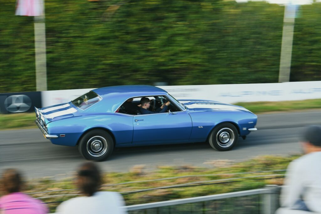 Blue classic car with white stripes driving fast driving