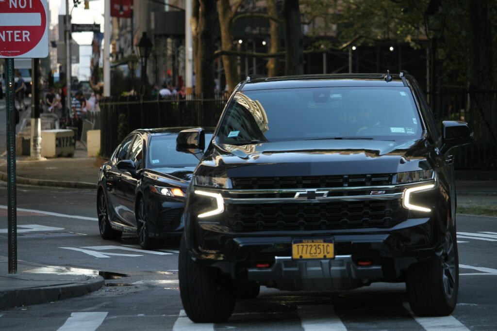A black truck driving down a street next to a no parking sign