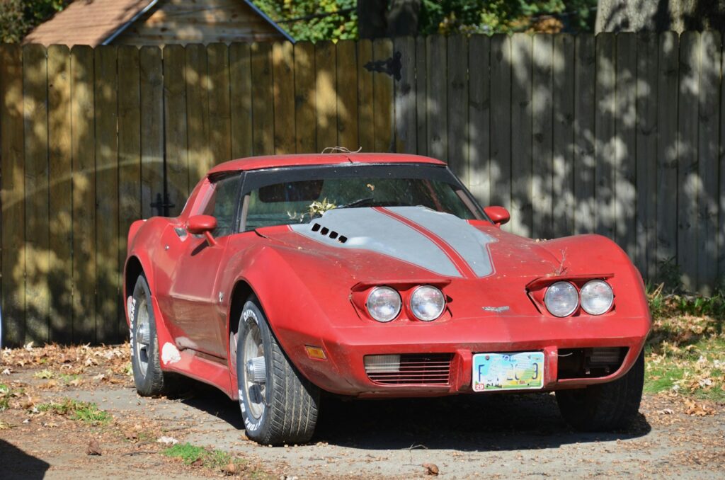 a red sports car parked in front of a wooden fence