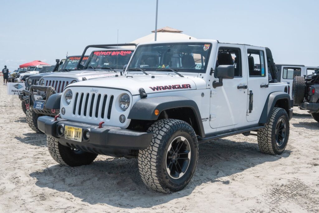 A row of Jeep Wranglers parked on sandy Wildwood beach, NJ, under sunny skies.