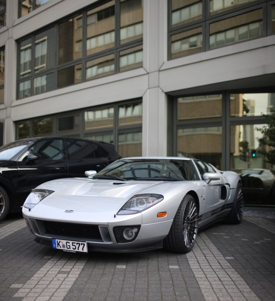 Silver Ford GT sports car parked in an urban lot, showcasing luxury and style.