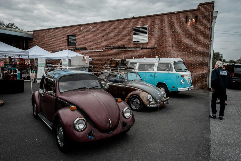 Classic Volkswagen Beetles and minivan showcased at an urban motor show.