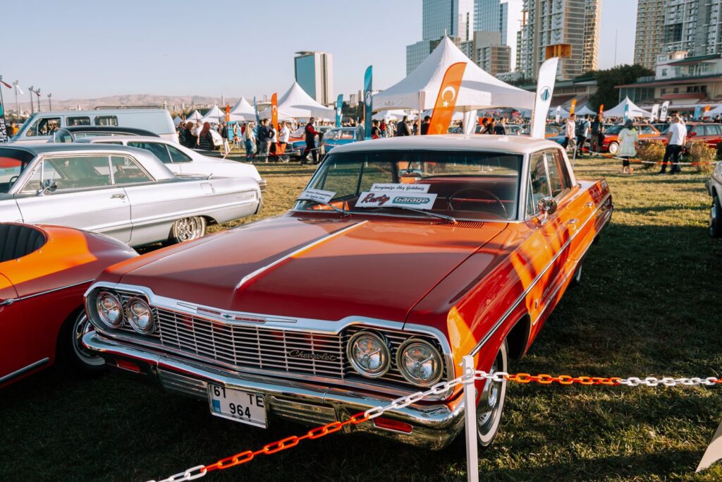 A vibrant Chevrolet Impala showcased at an outdoor vintage car exhibition.