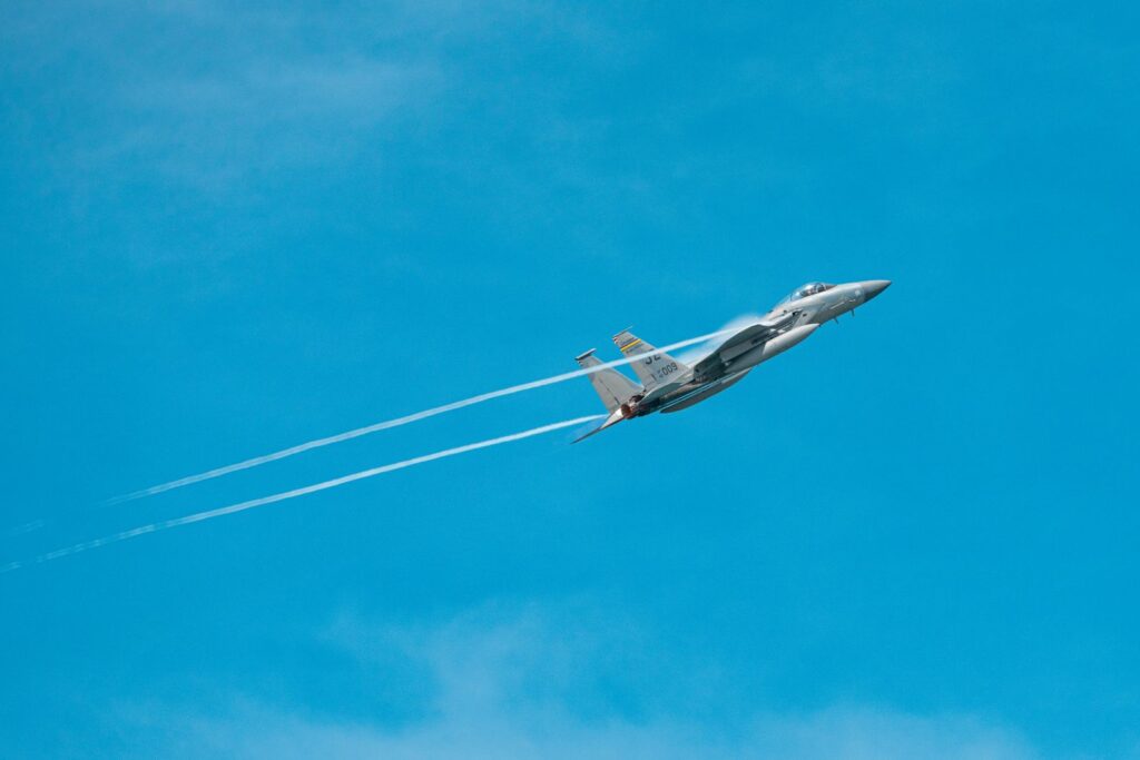 Dynamic image of a fighter jet soaring through a clear blue sky, leaving contrails.