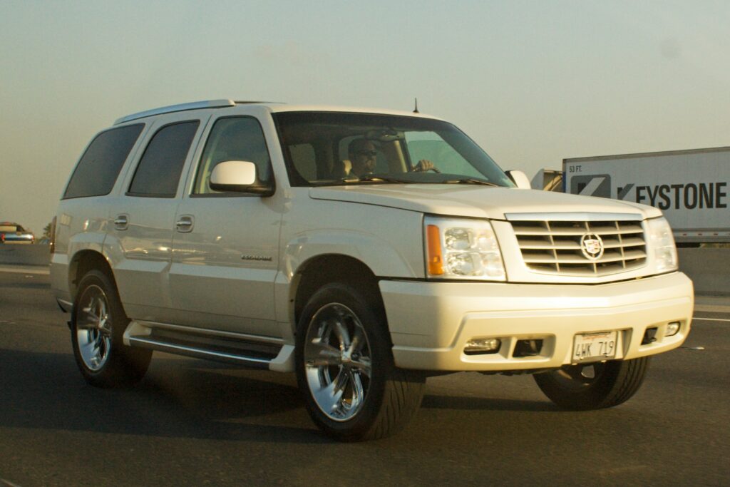 White cadillac escalade driving on a highway.