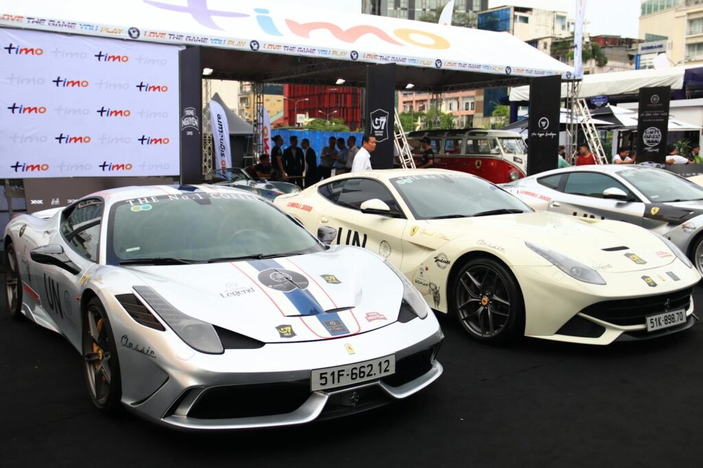 High-end sports cars showcased at an outdoor automotive event, drawing a crowd.